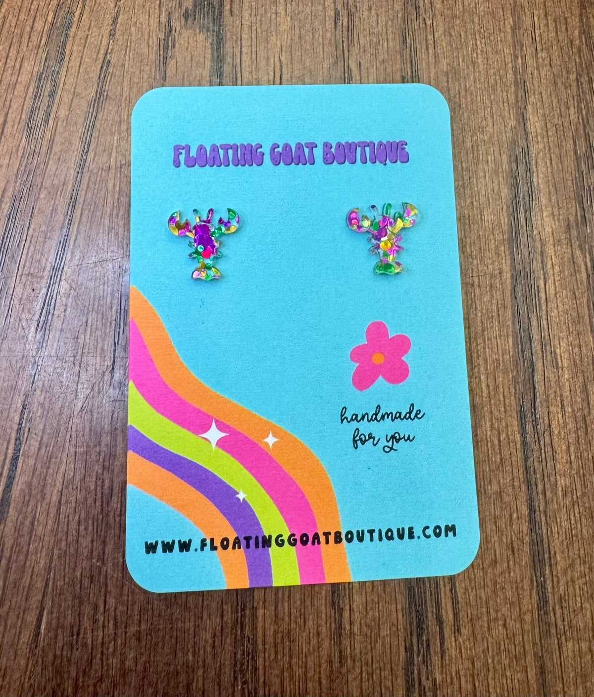 Earring card with Crawfish Mardi Gras Confetti earrings and 'Floating Goat Boutique' branding on a wooden surface.