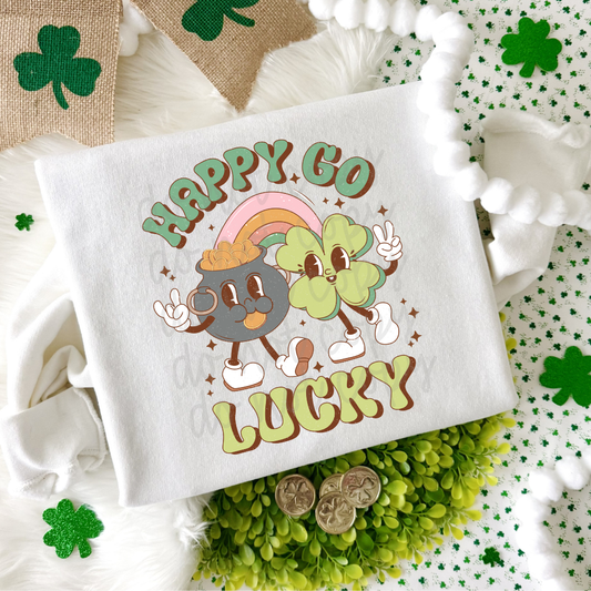 Happy Go Lucky St. Patrick’s Day graphic tee featuring retro shamrock and pot of gold characters with rainbow design on white Bella Canvas or Comfort Colors shirt.
