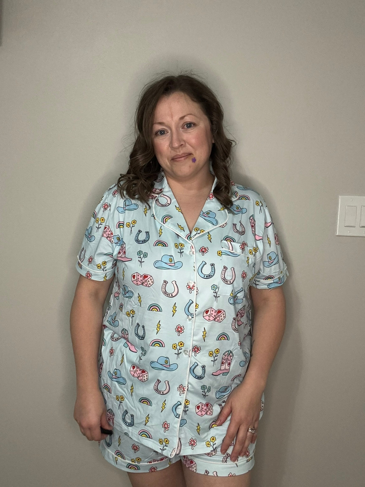 Woman wearing a cowgirl patterned pajama set against a plain wall.